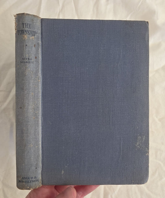 Vintage book titled 'The Township' held by a hand on a textured white background