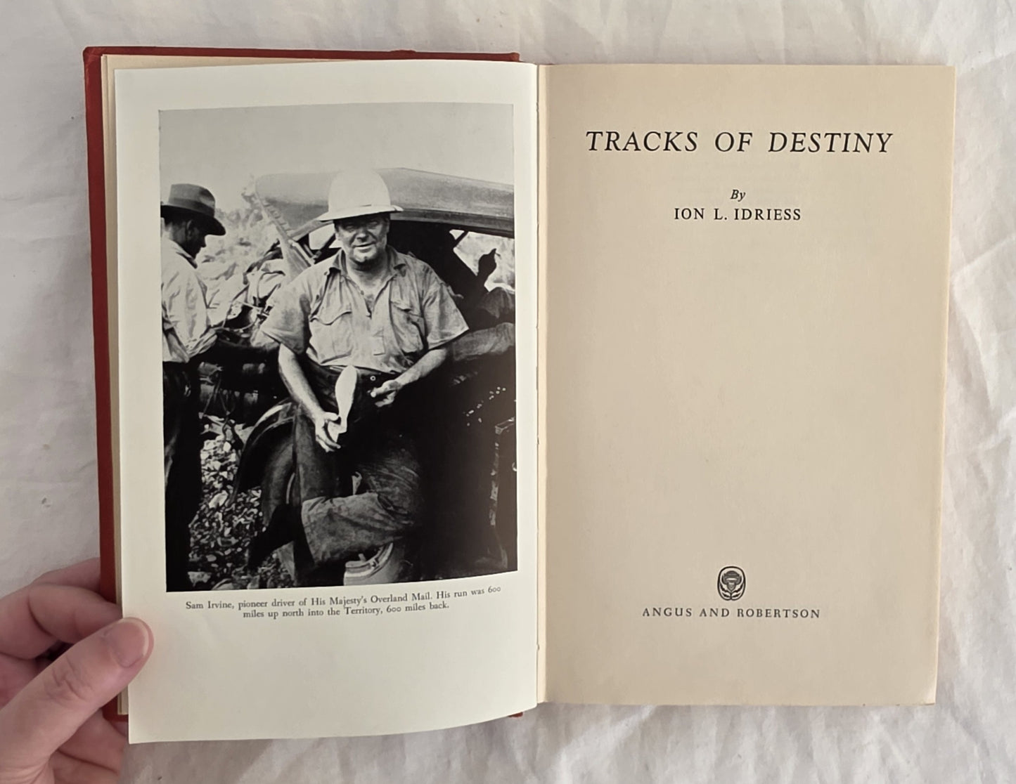 Open book titled 'Tracks of Destiny' by Ion L. Idriess, held against a white background.