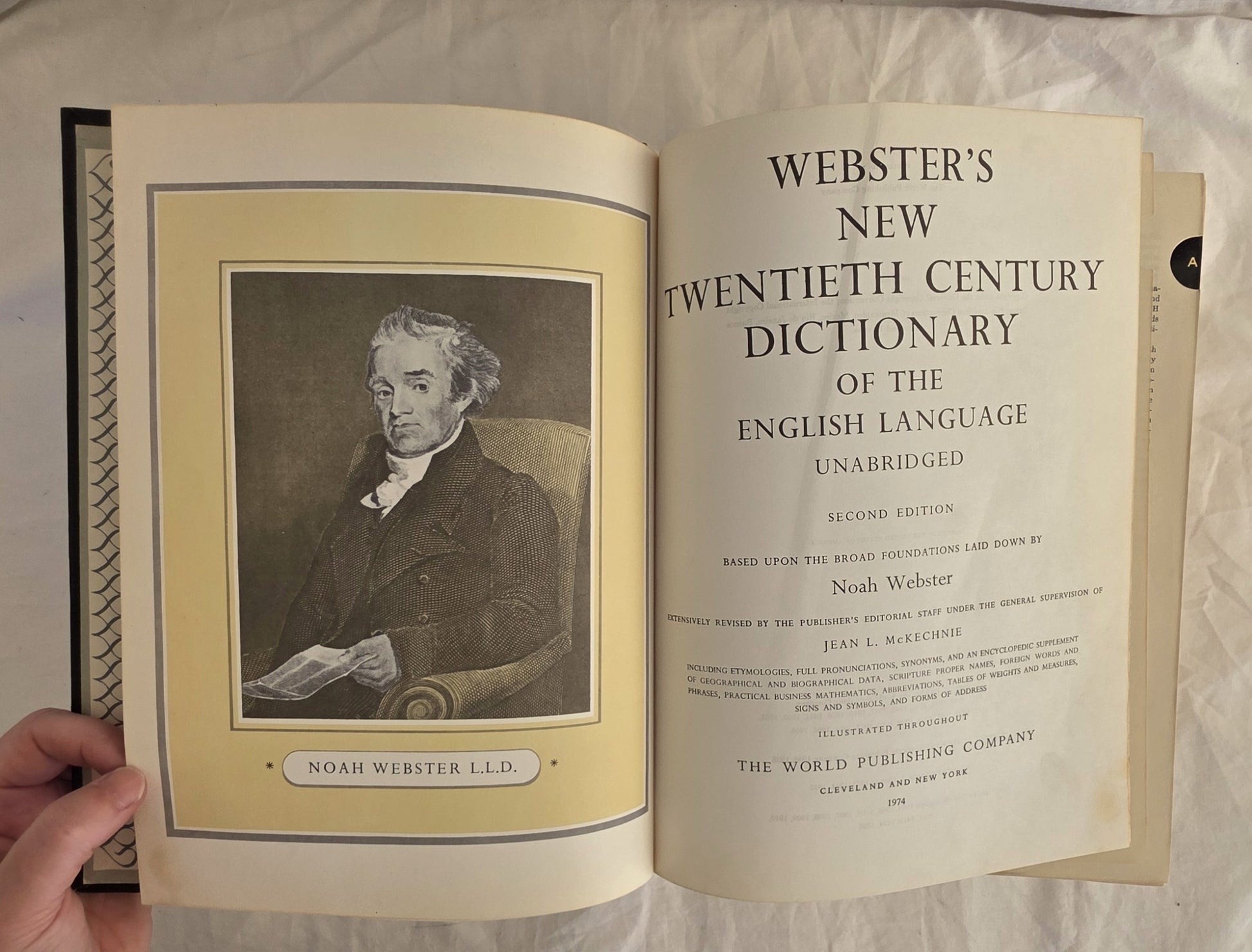 Open book displaying the cover of Webster's New Twentieth Century Dictionary on a textured surface.