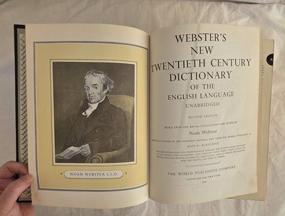 Open book displaying the cover of Webster's New Twentieth Century Dictionary on a textured surface.